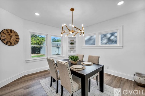 A dining room with a table set for four and a chandelier hanging from the ceiling.