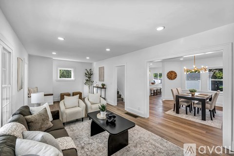 A living room with a black coffee table and a dining table with chairs.