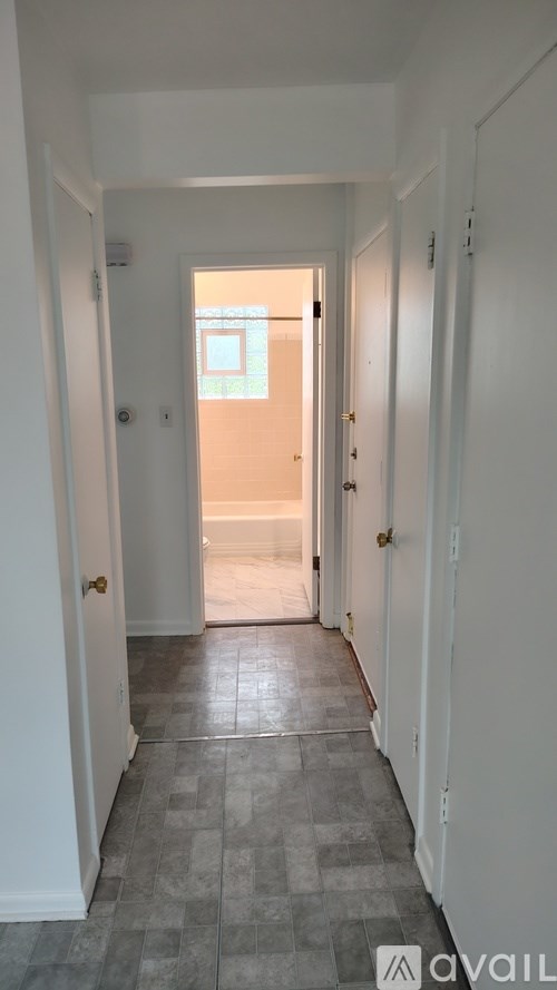 A hallway with a tiled floor and white walls.