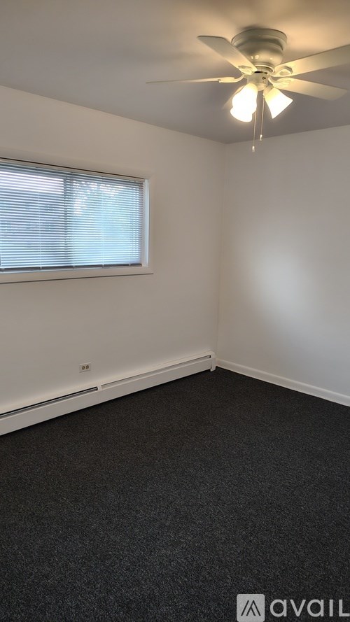 A room with a ceiling fan and a window with blinds.