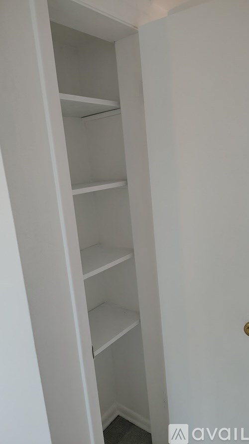 A white open closet with shelves and a door.