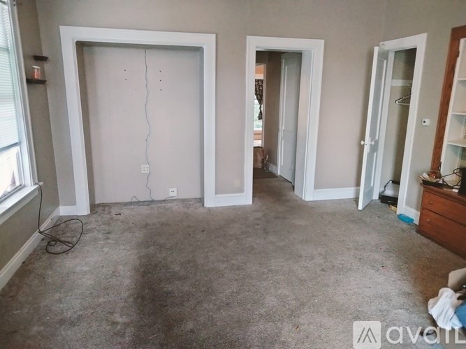 A room with a large white door and a smaller door to the right, both with cracked walls.