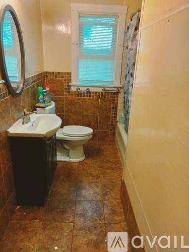 A bathroom with brown tiles and a white toilet.