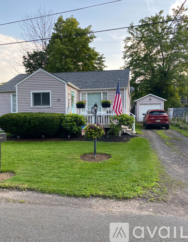 A house with a flag on the front porch and a car parked in the driveway.