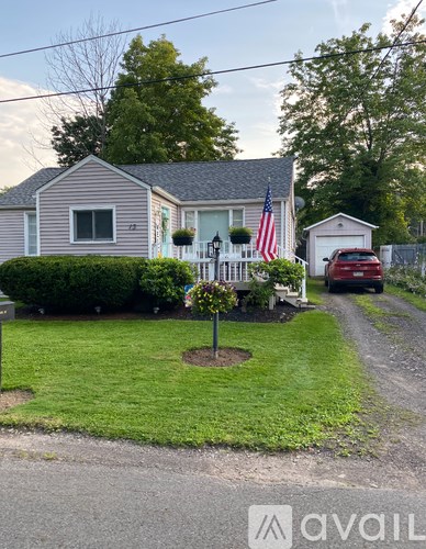 A house with a flag on the front porch and a car parked in the driveway.