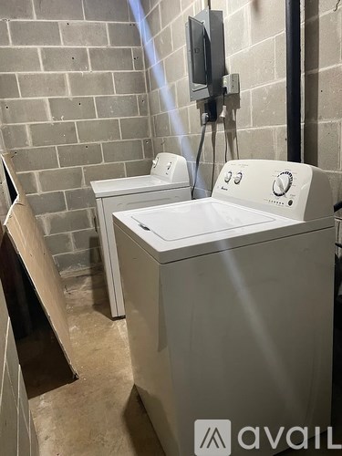 Two washing machines in a room with a brick wall.