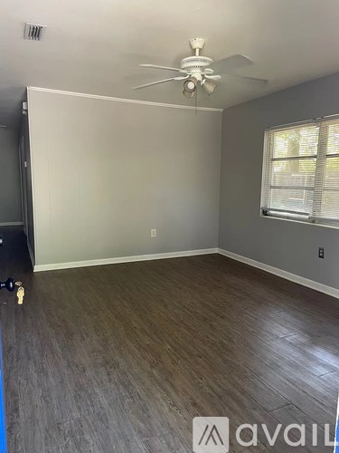 A room with a ceiling fan and a window with blinds.