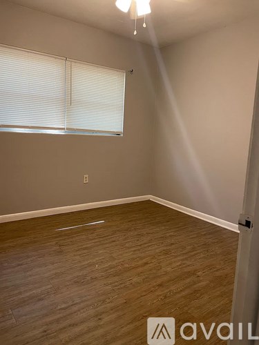 A room with wooden flooring and a window with blinds.