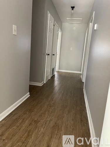 A long hallway with wood floors and white walls.