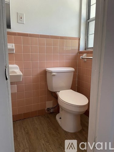 A white toilet in a bathroom with pink tiles.