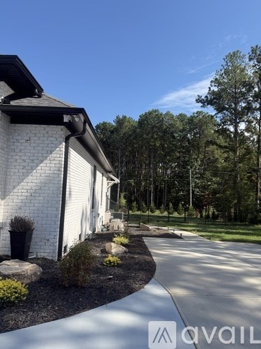 A white house with a black roof and a driveway in front.