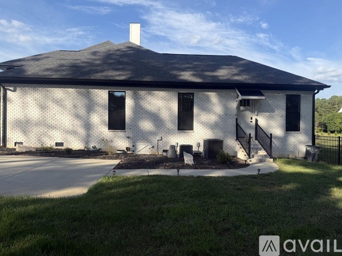 A white house with a black roof and a chimney.