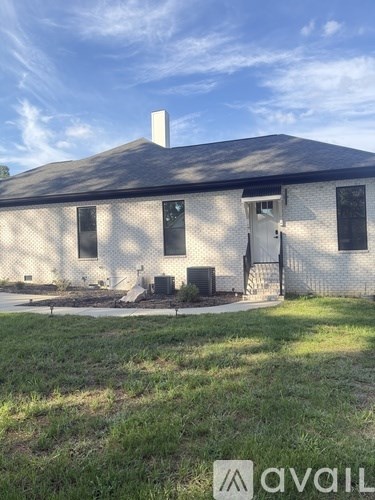 A white house with a black roof and a chimney.