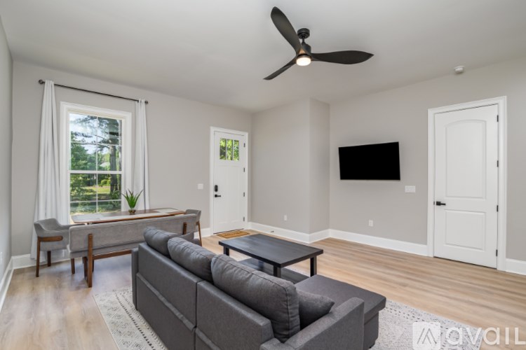 A living room with a grey couch and a ceiling fan.