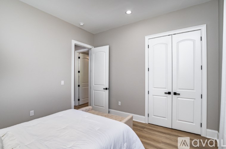 A bedroom with a bed, a mirror, and two doors.