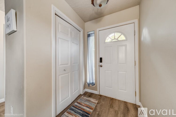 A hallway with a white door and a window with curtains.