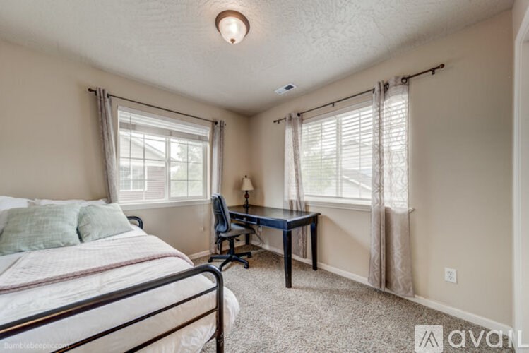 A bedroom with a bed, desk, and chair.