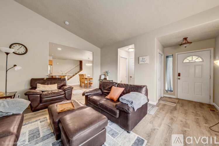 A living room with brown leather furniture and a clock on the wall.