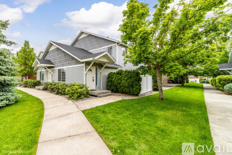 A house with a grey roof and a green lawn in front.