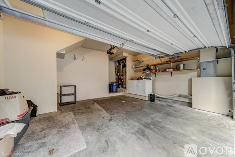 A room with a concrete floor and white walls, with a few items scattered around, including a cardboard box and a blue container.