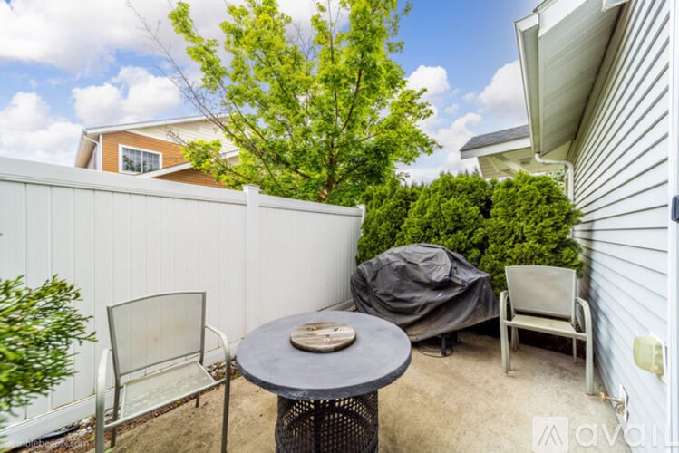 A patio with a table, chairs, and a grill.