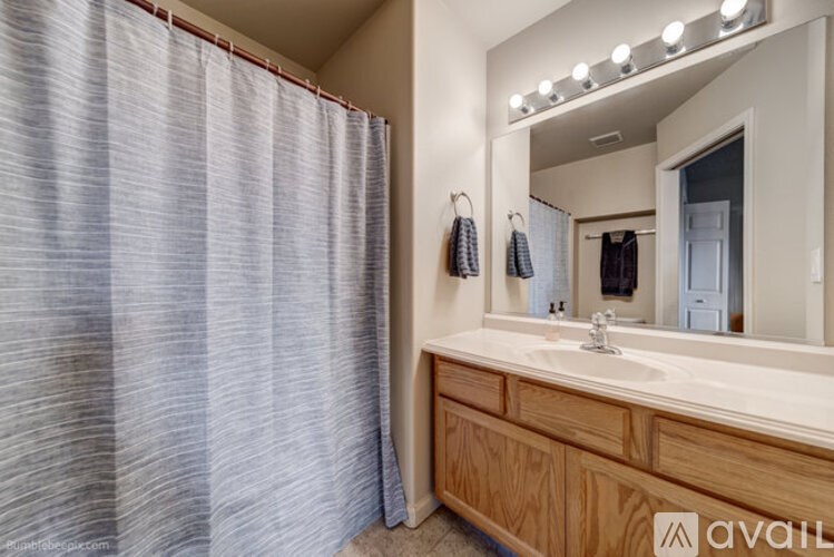 A bathroom with a wooden vanity and a mirror with lights above it.