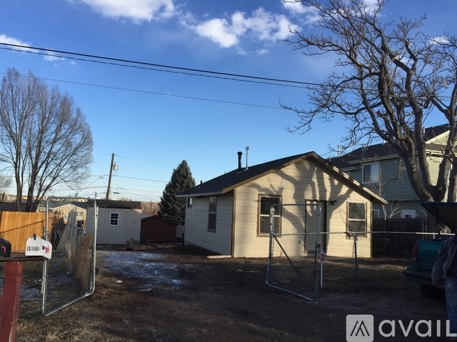 A house with a fence and a tree in front of it.