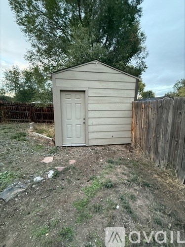 A shed sits in a yard with a wooden fence.