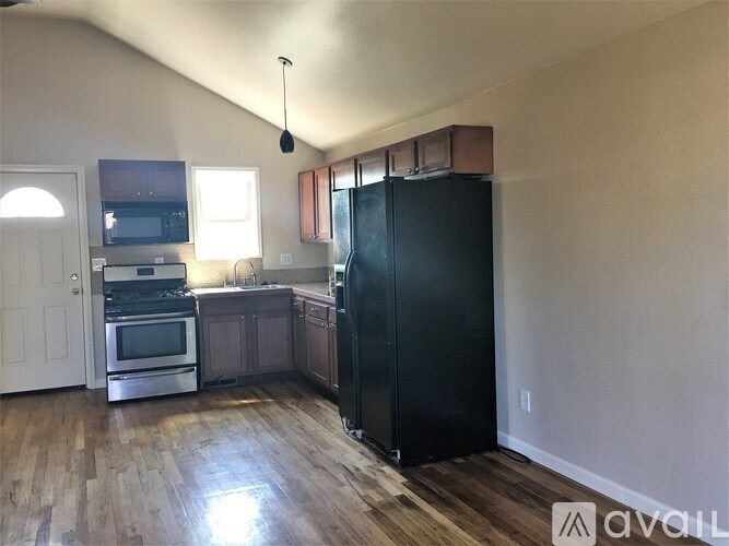A kitchen with a black fridge, stove, and microwave.