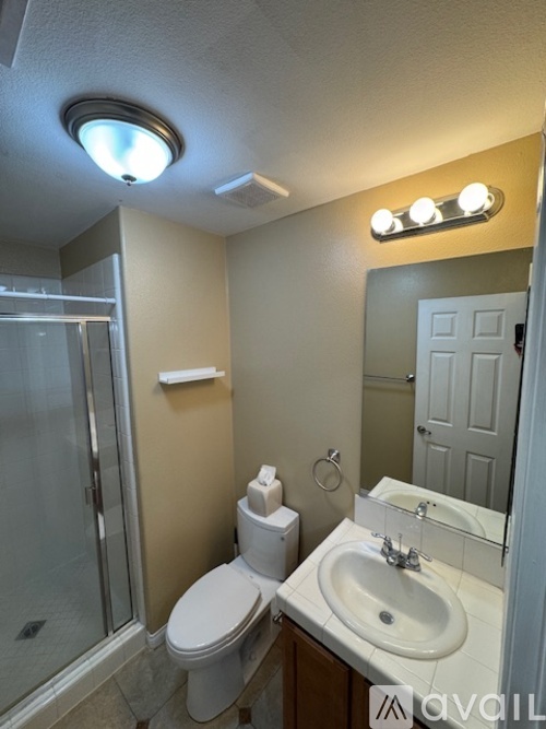 A bathroom with a toilet, sink, mirror, and shower.