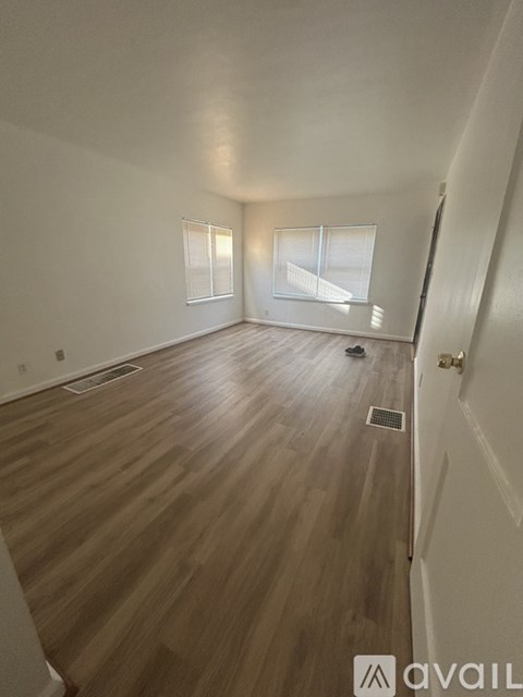 A room with wooden flooring and a person standing in the middle.