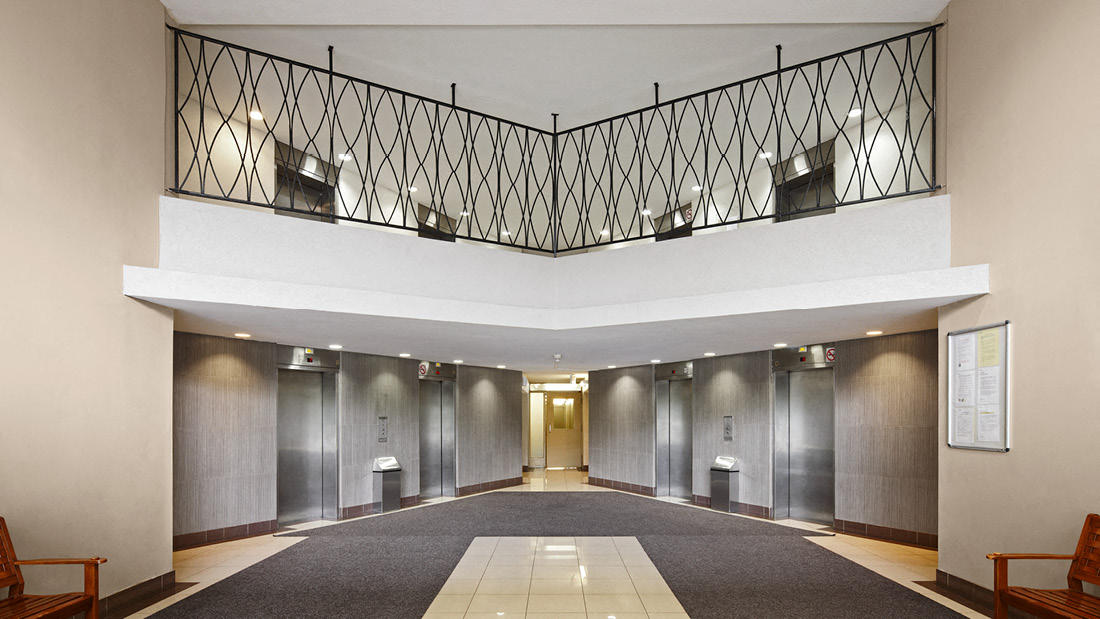 A hallway with a black railing and a white ceiling.