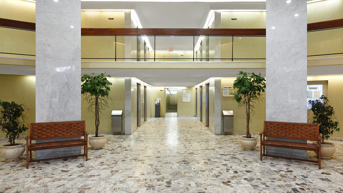 A hallway with marble floors and benches on either side.