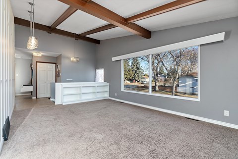 A spacious living room with a white sofa and a large window showing an outdoor view.