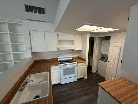 A kitchen with white cabinets and a wooden countertop.