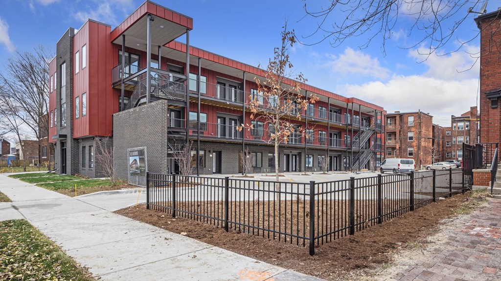 A modern red and grey building with a black fence in front.