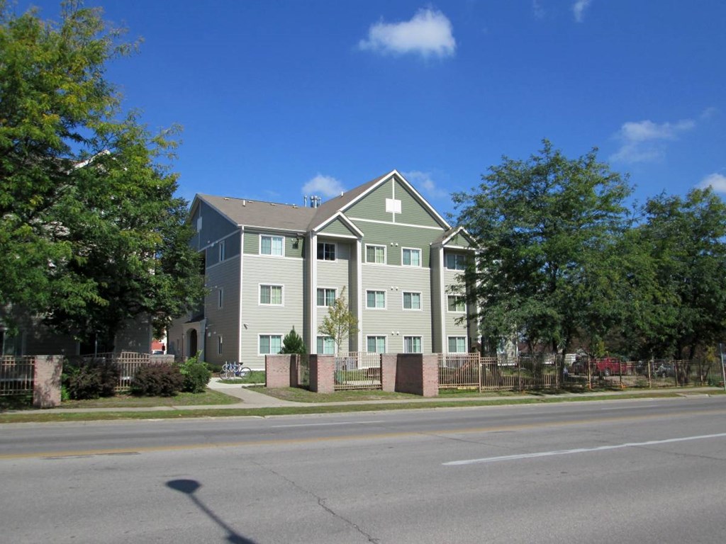 A grey building with a green roof is surrounded by trees.