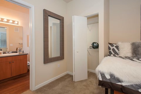 A bedroom with a bed, dresser, mirror, and a nightstand with a lamp.