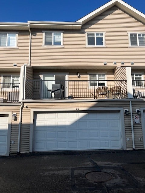 A tan two story apartment building with a balcony and a garage.