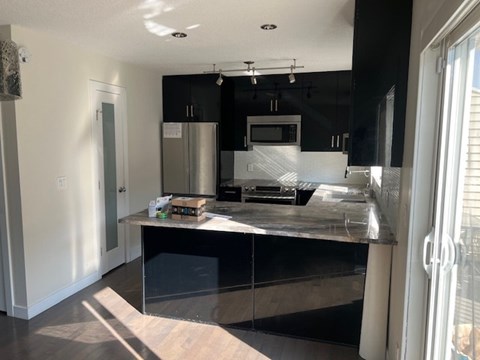 A modern kitchen with a stainless steel refrigerator and microwave.
