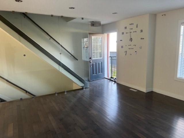 A large empty room with a staircase and a clock on the wall.