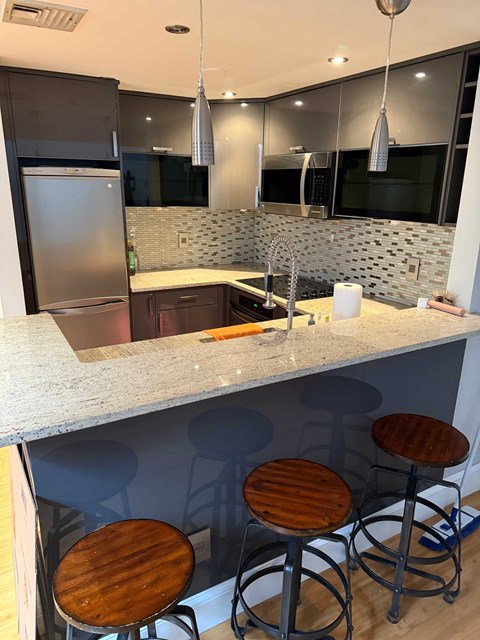 A kitchen with a bar stool and a refrigerator.