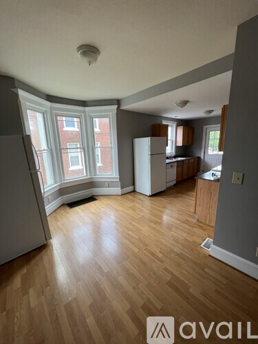 A kitchen with wooden floors and a window overlooking a brick building.
