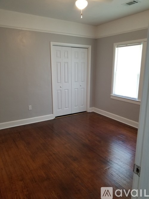 A room with a white door and wooden flooring.