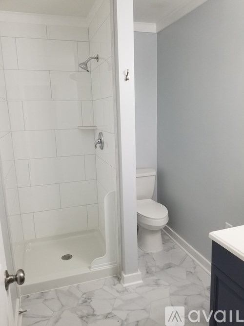 A white tiled bathroom with a toilet and a walk in shower.