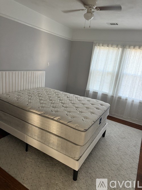 A bed with a white mattress is in a room with a ceiling fan.