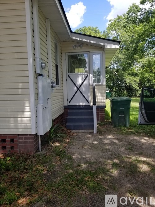 A house with a white door and a green trash can.