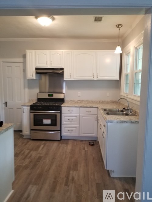 A kitchen with white cabinets and a wooden floor.