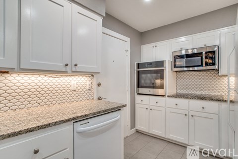A kitchen with white cabinets and a tiled backsplash.