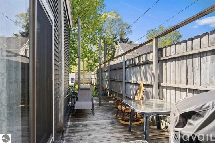 A balcony with a table and chairs overlooking a wooden fence.